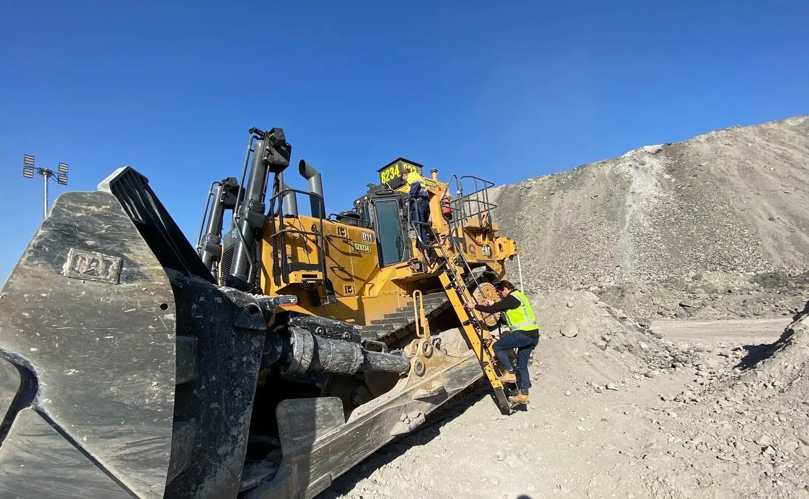 A worker climbing onto a dozer on a mine site