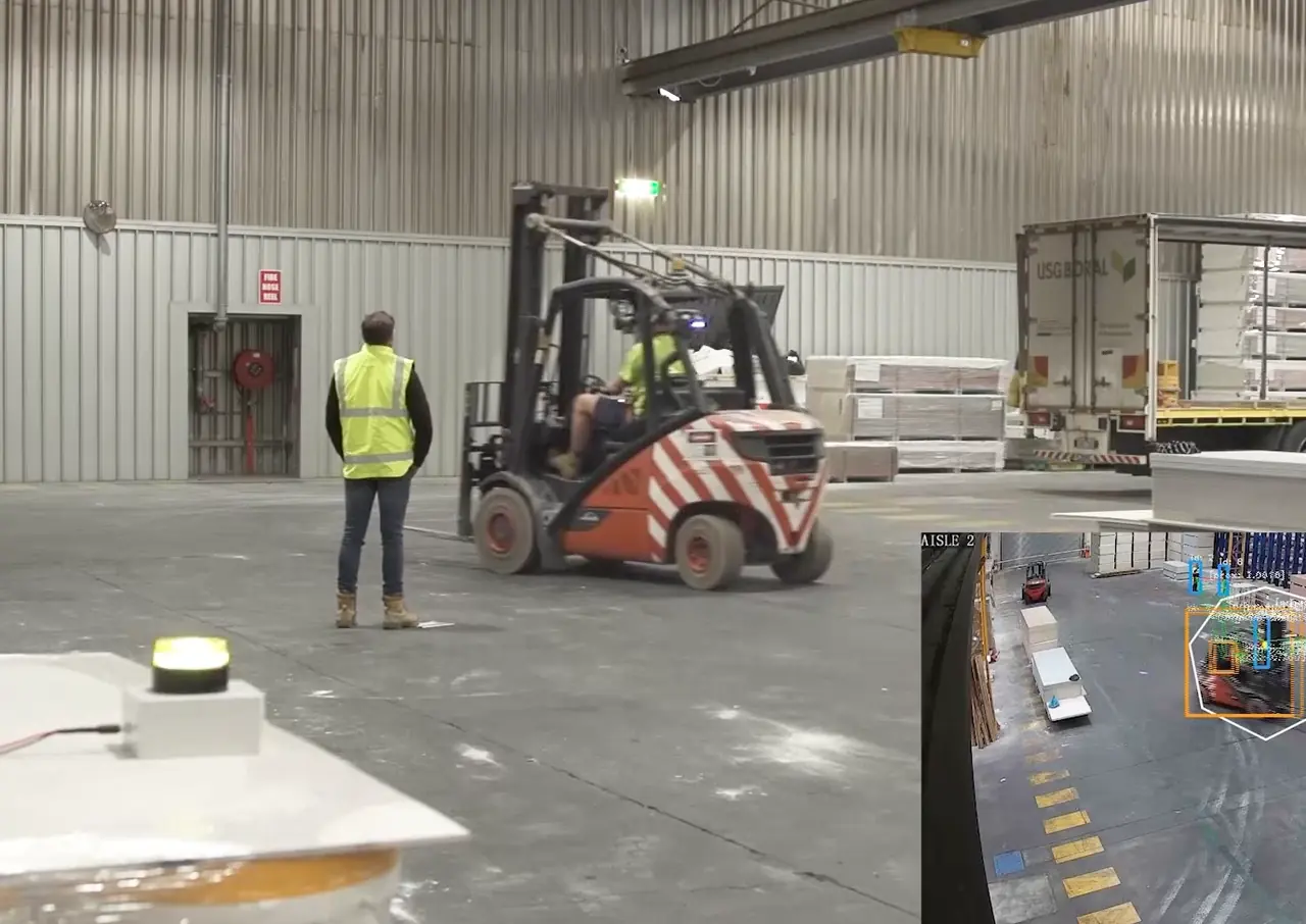 A forklift and a worker on a plant floor, with the WARNY camera view inset