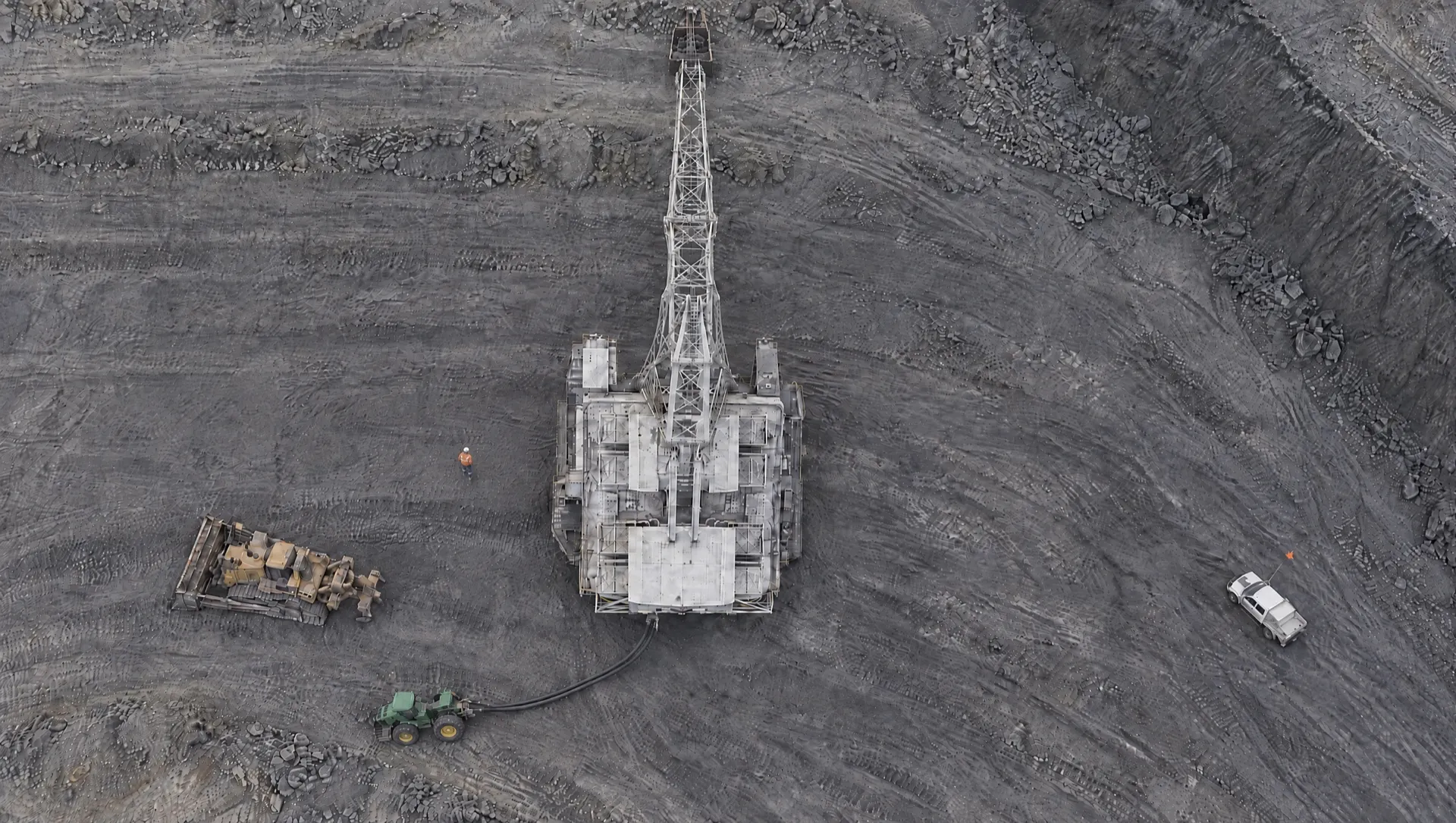 Illustration: a dragline from directly above, with the area the operator can see from the cab, ahead and to the right, left clear and everything else shaded: a person on foot on its left, a Caterpillar D10 dozer, a John Deere cable tractor towing the trailing cable from the rear, and a light vehicle, all out of sight